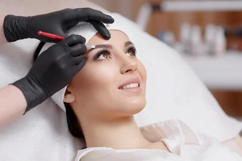 young woman smiling while microblading eyebrows