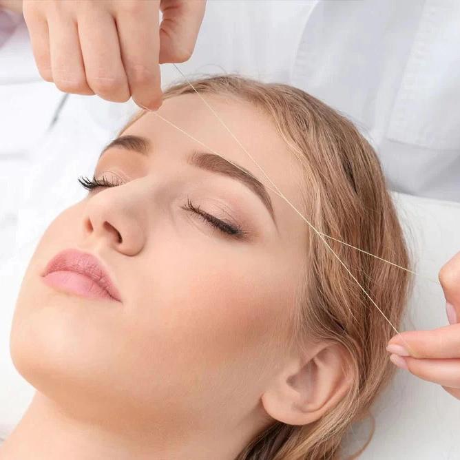 young woman getting threading on her eyebrows